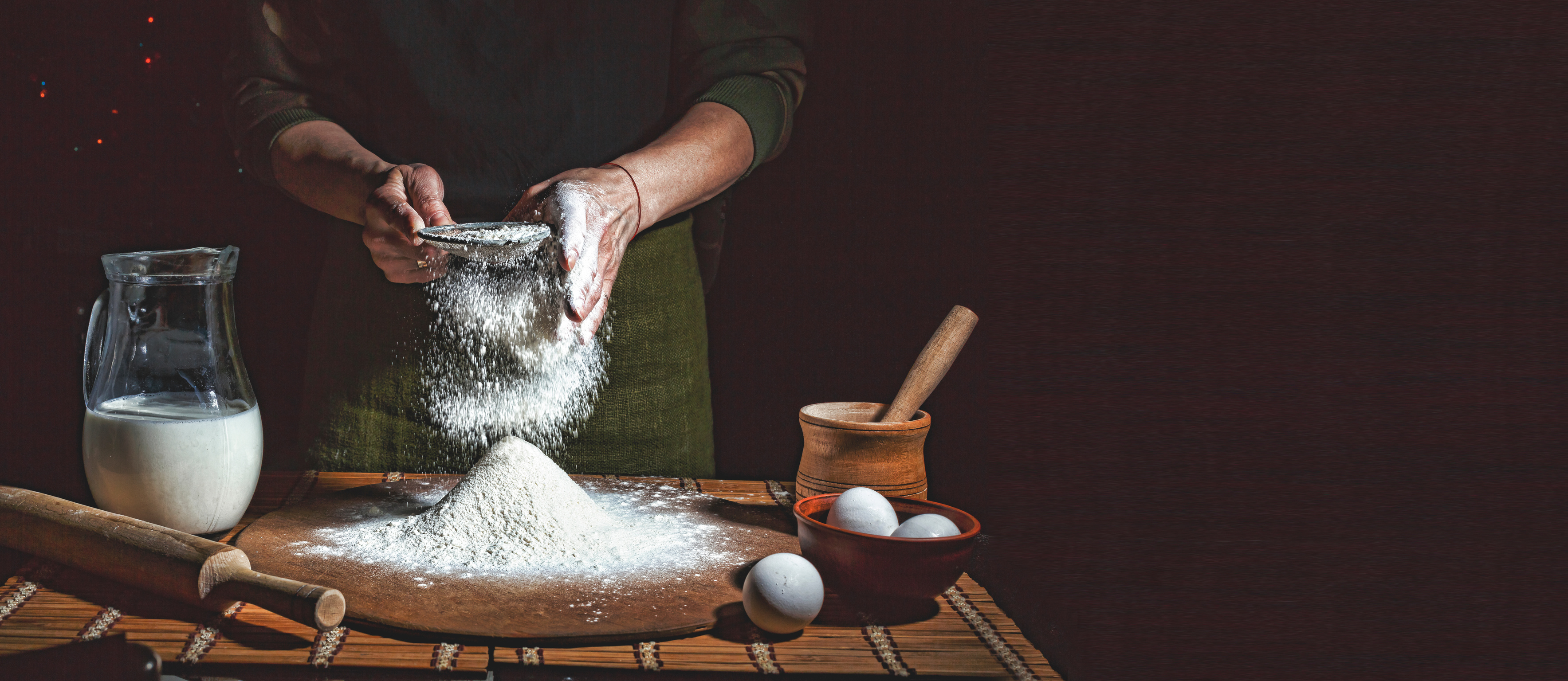 Preparation of bread dough. Bakery, baker's hands, flour is poured, flying flour